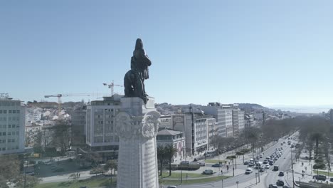 aerial, rising, drone shot, tilting towards the marques de pombal statue revealing liberty avenue with some traffic, in lisbon city, sunny day, in lisboa, portugal