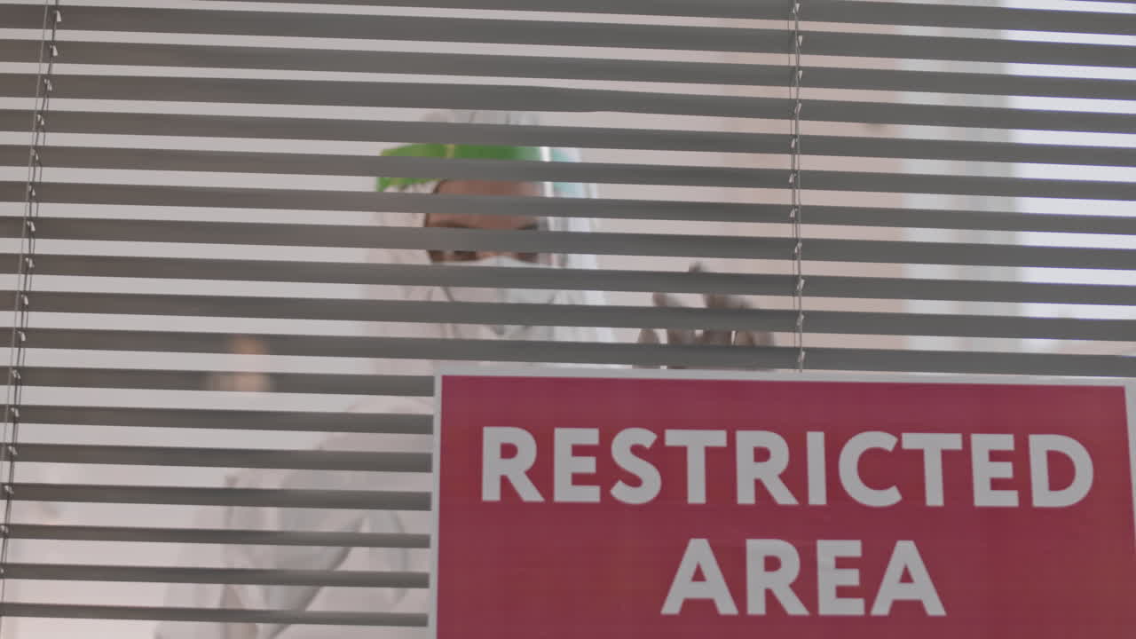 Doctor Looking Through Horizontal Blinds