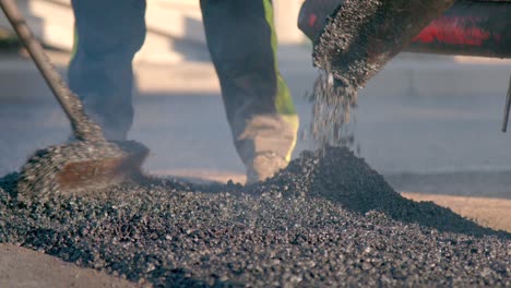 paving machine distributes hot asphalt onto the road while workers spread it out