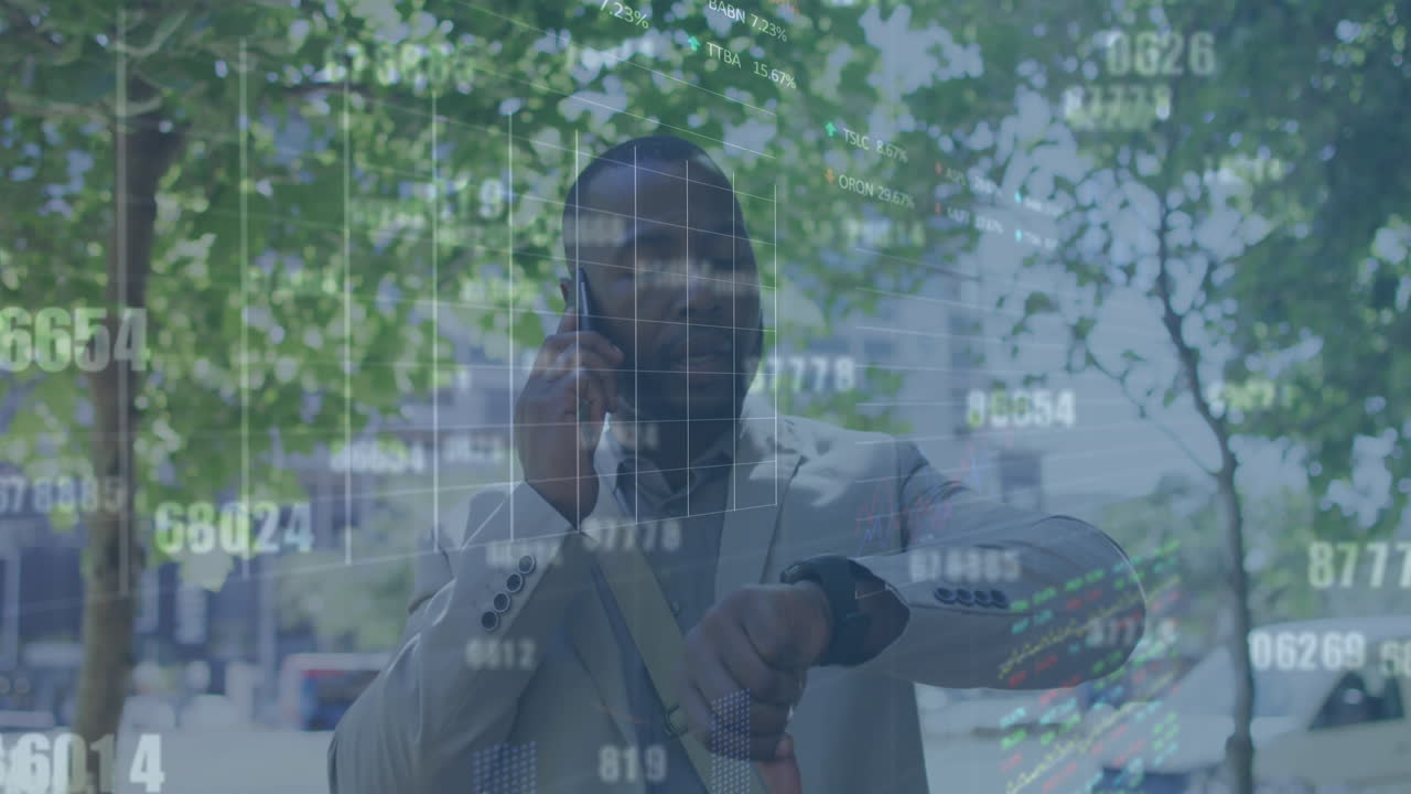 Animation of graphs, trading board, african american man talking on phone and looking at smartwatch