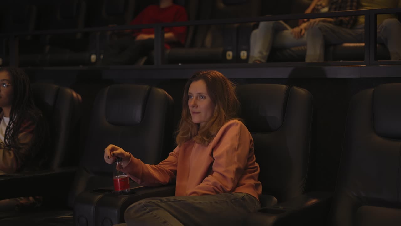 mujer sentada en un sillón viendo una película en el cine sola, vista lateral