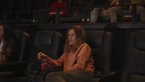 Frau-Sitzt-Im-Sessel-Und-Schaut-Sich-Allein-Im-Kino-Einen-Film-An,-Seitenansicht