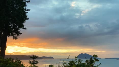 timelapse of beautiful sunset over sea with islands in the background and trees in the foreground