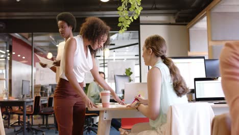 mujeres de negocios diversas sentadas en el escritorio, discutiendo el trabajo en la oficina, en cámara lenta