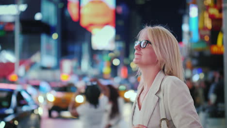 Attractive-Woman-Admiring-The-Lights-Of-The-Famous-Time-Square-In-New-York-Yellow-Cabs-Passing-By---