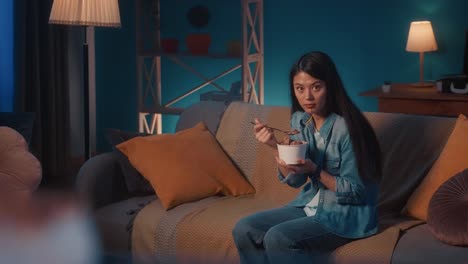woman eating ice cream on the sofa at night