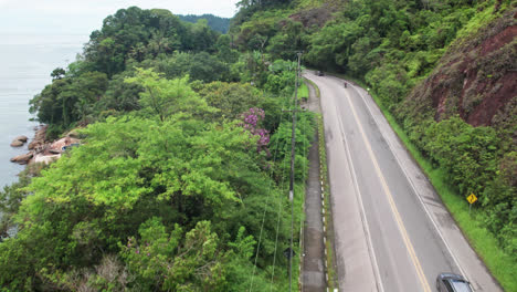 Fast-Aerial-flying-over-road-along-coast-of-Ubatuba-on-partly-cloudy-day,-Brazil