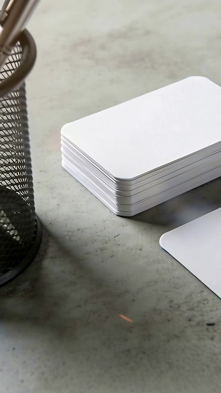 Vertical video: Moving camera capturing stacked rounded white cards on desk with loose card, pen