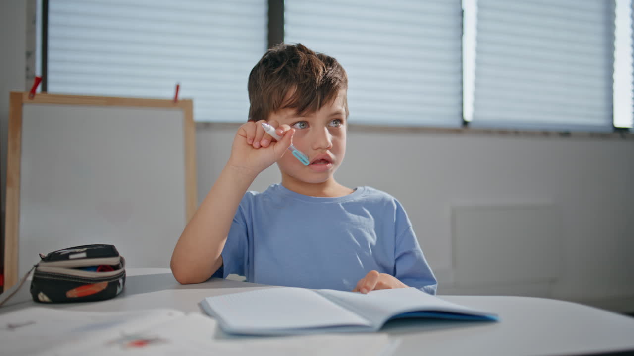 School child solving test sitting desk at class room closeup. Boy schooling