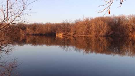 a slow glad across a still lake with a bench on a rock out in the distance
