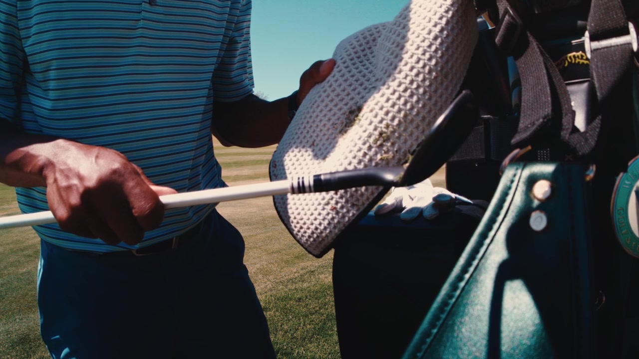 Un golfista afroamericano va a pulire la mazza sull'asciugamano e sul guanto appesi su un campo desertico soleggiato al rallentatore, un primo piano dettagliato in 4k a 800fps al rallentatore.