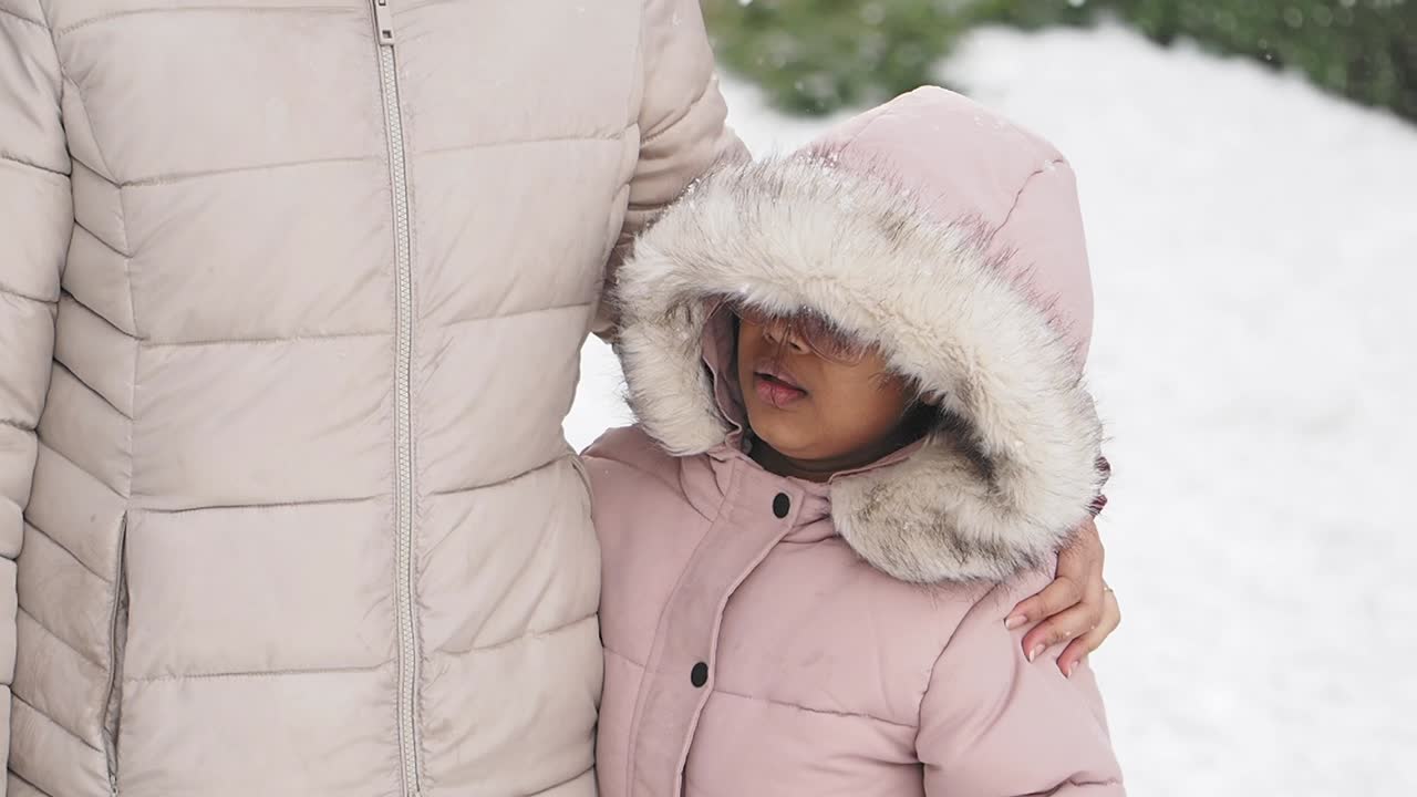 Adult and child in winter coats standing in snow