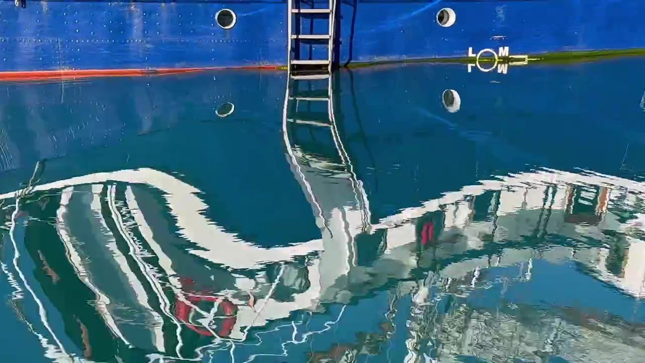 Reflexos abstratos de escuna na superfície da água em um dia ensolarado de verão em Scoresbysund, Groenlândia