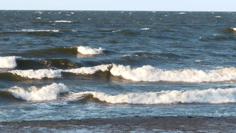 Rough-ocean-waves-hitting-sandy-beach-in-cold-and-icy-season,-slow-motion