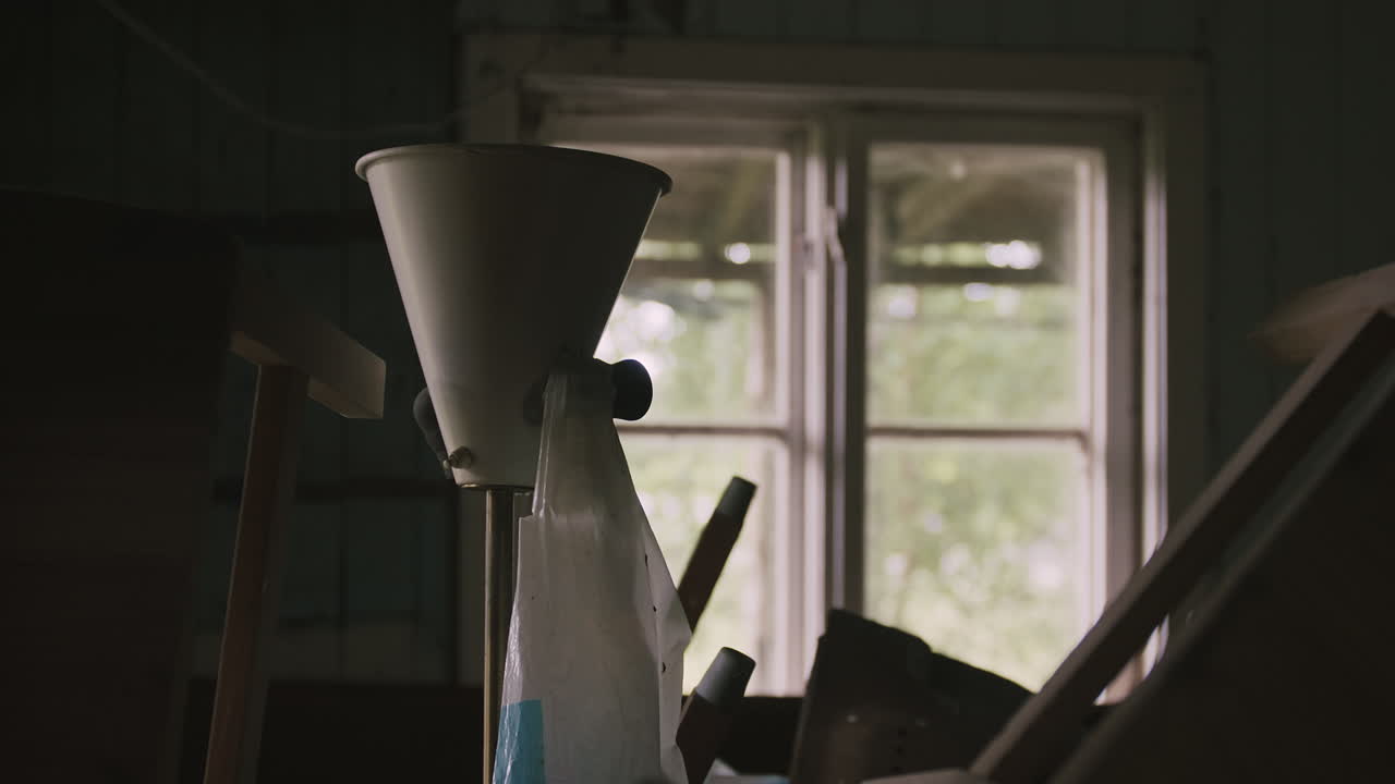 Yksityiskohtainen näkymä vintage-lampusta rojun keskellä, luonnonvalon valaistessa rikkoutuneesta ikkunasta.