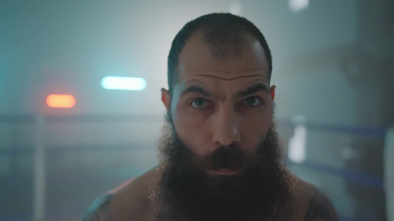 Primo piano di uomo barbuto con sguardo intenso sul ring di boxe