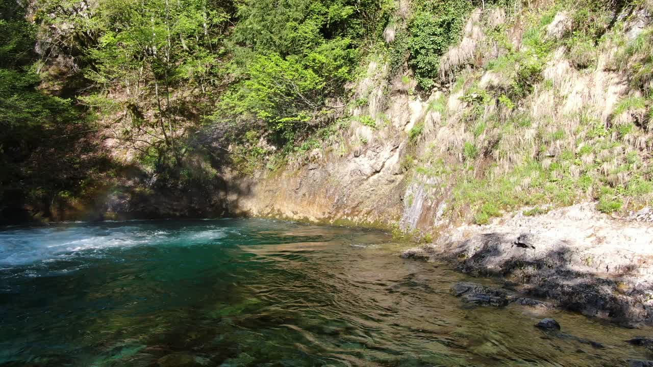 vista de aviones no tripulados en albania en los alpes volando frente a una cascada rodeada por la montaña rocosa y verde en el