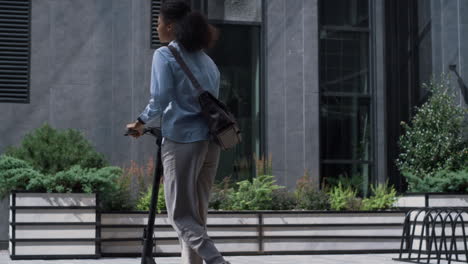 employee riding electric scooter at office building sunny day. daily commute.