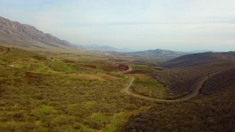 Drone-shot-over-scenic-landscape-of-mountain-wild-nature-plain-dry-climate-and-local-road-for-nomad-people-who-live-in-traditional-tent-lifestyle-is-sustainable-friend-with-wildlife-support-food-bread