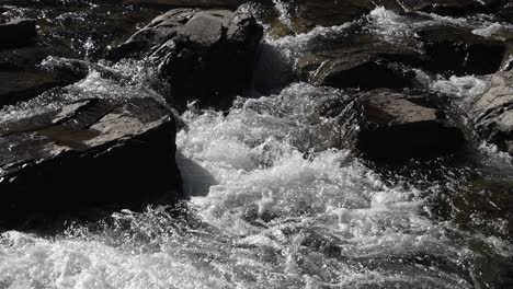 a flowing river glides over rocks, creating splashes and dynamic water patterns. slow motion