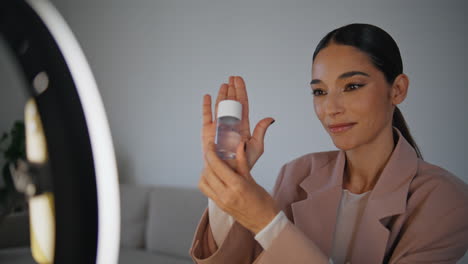 talking blogger showing cosmetic to mobile phone closeup. woman filming tutorial