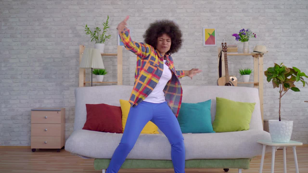 African american woman with an afro hairstyle uses a smartphone got good news about winning and dancing