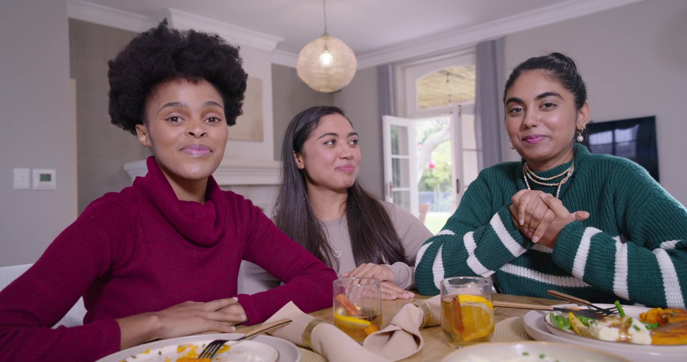 Diverse women friends sharing meal at table left woman in maroon sweater speaking middle pointing