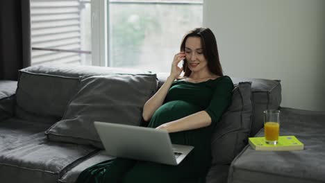 Mujer-De-Negocios-Embarazada-Hablando-Por-Teléfono-Móvil-En-La-Oficina-De-Casa-Mientras-Trabaja-En-Una-Laptop