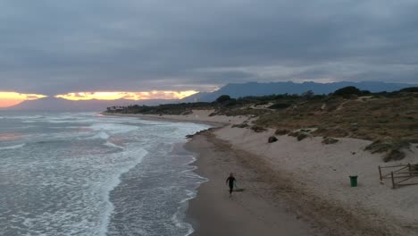 Aerial-views-over-a-beach-with-gentle-waves-and-people-walking-along-the-shore-calmly