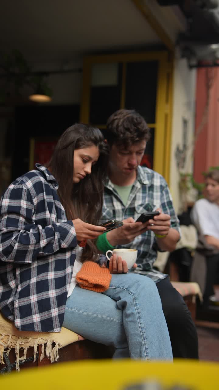 una pareja joven usando teléfonos inteligentes en un café