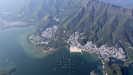 varios yates de recreo están anclados en las claras aguas azules de tai mei tuk en la playa del pueblo de long mei entre las altas montañas verdes