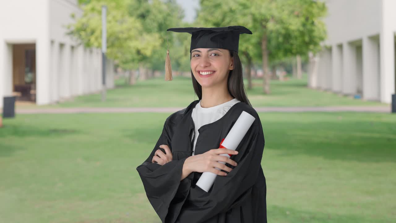 retrato de una feliz chica graduada de la universidad india de pie con las manos cruzadas