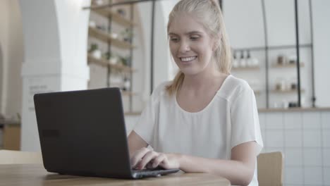 mujer joven alegre que usa una computadora portátil en el interior de trabajo conjunto