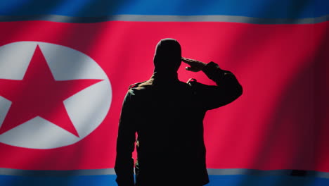 Secret-intelligence-agent-doing-saluting-hand-gesture-towards-North-Korea-flag