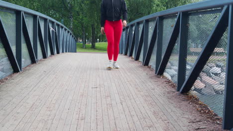 young girl walking across a bridge in a park