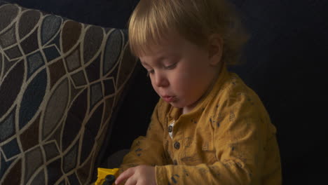 niño pequeño sentado en un sofá jugando con un camión de juguete