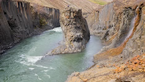 static shot of person on a basalt stack in studlagil canyon in east iceland