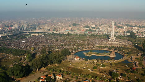 thousands of people gather at greater iqbal park with minar-e-pakistan monument in lahore, punjab, pakistan