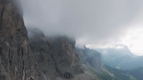 Aerial-view-of-the-rugged-mountain-range-in-Passo-Gardena-covered-in-clouds-in-the-Dolomites-Mountains,-Trentino,-South-Tyrol,-Italy