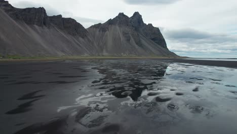 fotografía aérea de las montañas en stokksnes con sus reflejos en el agua durante el verano en islandia