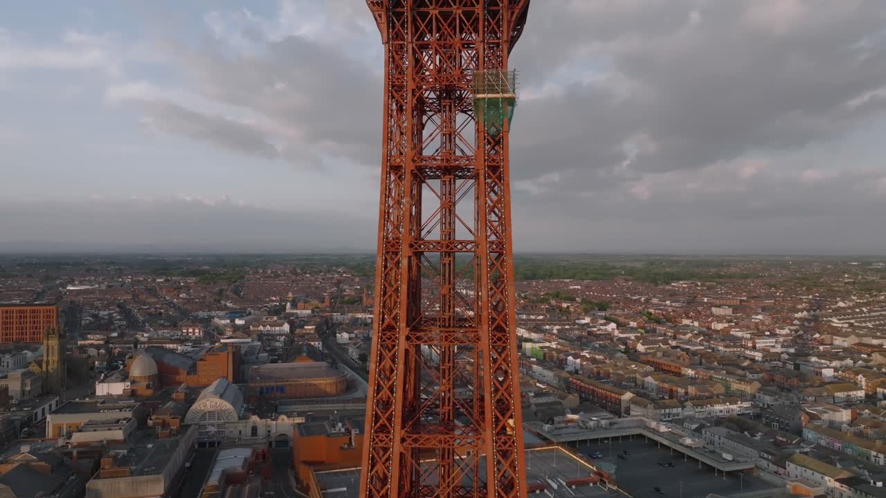 Blackpool Tower front face with rise revealing observation deck and urbanisation behind at golden hour. Lancashire, UK.