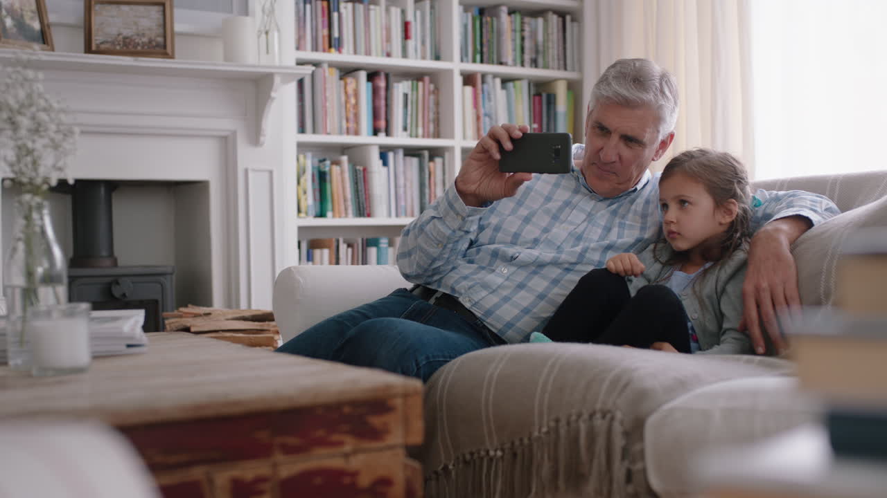 grandfather and child having video chat using smartphone little girl sharing vacation weekend with family grandpa enjoying chatting on mobile technology at home with granddaughter