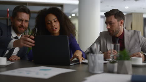 multiracial coworkers talking finance using laptop in modern company office.