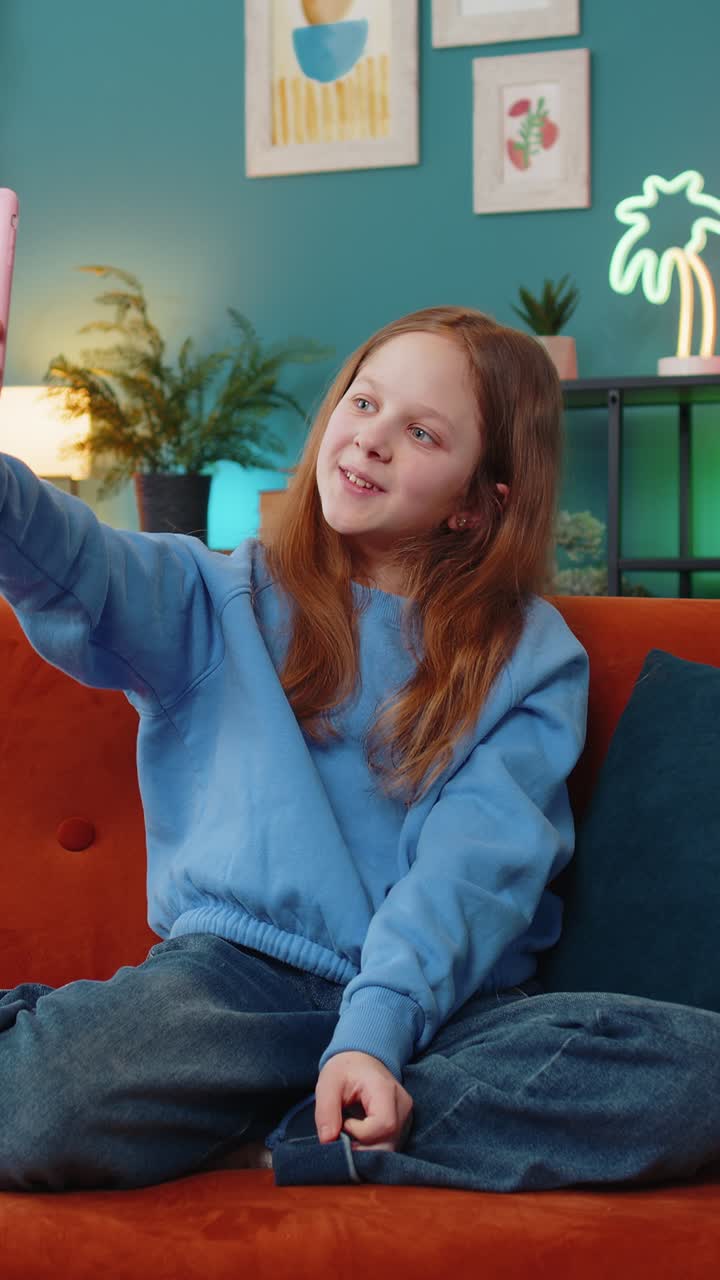 Happy child kid girl blogger communicating video call online taking selfie on smartphone at home