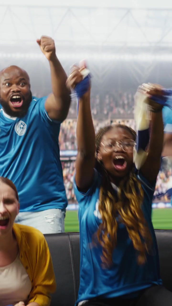 Video vertical: Aficionados al fútbol emocionados por un gol, sintiéndose transportados a las tribunas del estadio.