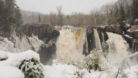 Wasserfall-Brüllt-Mit-Kraft-In-Einem-Schneesturm,-Schnee-Wirbelt-Um-Das-Herabstürzende-Wasser