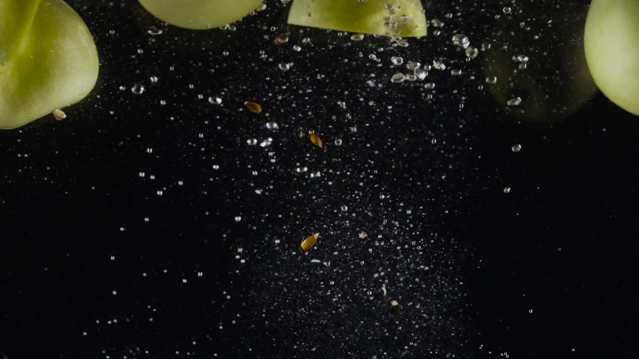 manzanas verdes y rebanadas de pepino salpicando en el agua