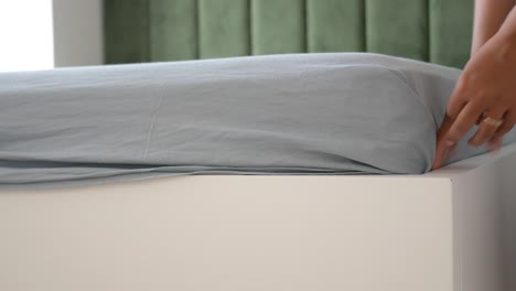 woman making bed: putting on fitted sheet and flat sheet