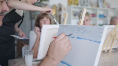 the teacher shows a group of friends of retired people in the elderly at drawing courses. a group of elderly men and women draw together and smile