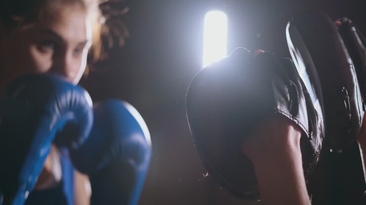 Bella donna praticante kickboxing si allena colpendo i colpitori in palestra, dimostrando grande forza e un fisico atletico; serie di kickboxer.